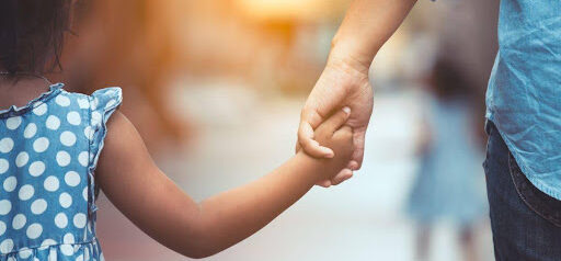 young girl holds dad's hand during a walk outside KHM Attorneys at Law Colorado Springs, Castle Rock