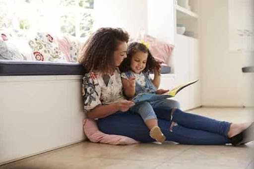 mother reads book to daughter while sitting on the floor in her home KHM Attorneys at Law Colorado Springs, Castle Rock