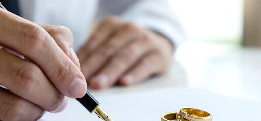 man signs prenuptial agreement while two wedding rings sit on paper KHM Attorneys at Law Colorado Springs, Castle Rock