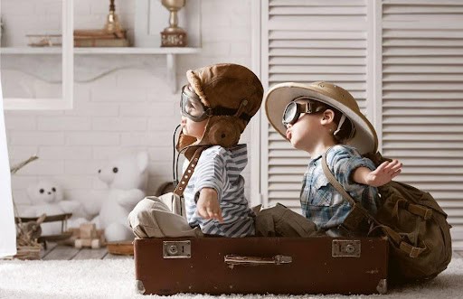 two children play "fly out of state" while wearing goggles and sitting in a suitcase KHM Attorneys at Law Colorado Springs, Castle Rock