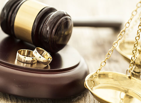close up of wedding rings near gavel with legal scale in background KHM Attorneys at Law Colorado Springs, Castle Rock