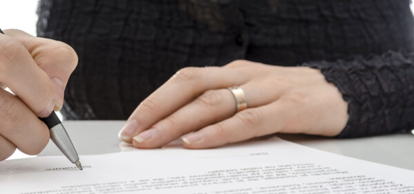 hero image of woman signing legal document KHM Attorneys at Law Colorado Springs, Castle Rock
