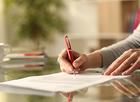 woman signs legal modification paperwork with red pen KHM Attorneys at Law Colorado Springs, Castle Rock