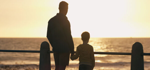 hero size image of father and son holding hands while watching sun set along beach KHM Attorneys at Law Colorado Springs, Castle Rock